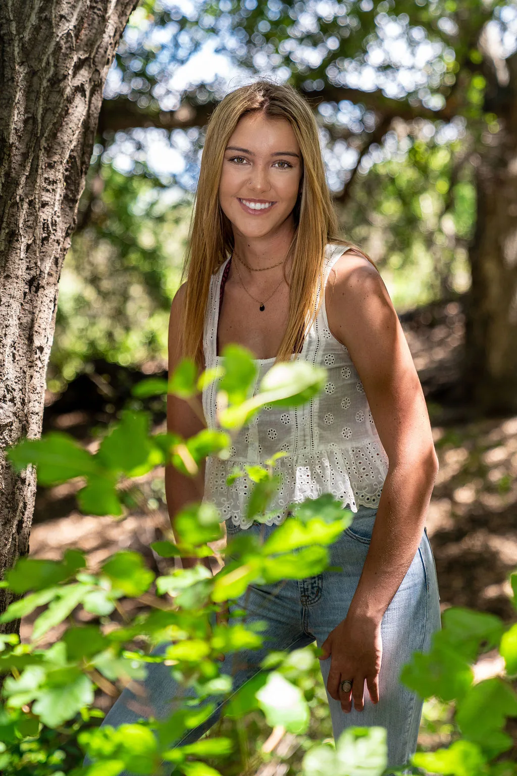 Young woman smiling through foliage, natural light lifestyle portrait in Southern California