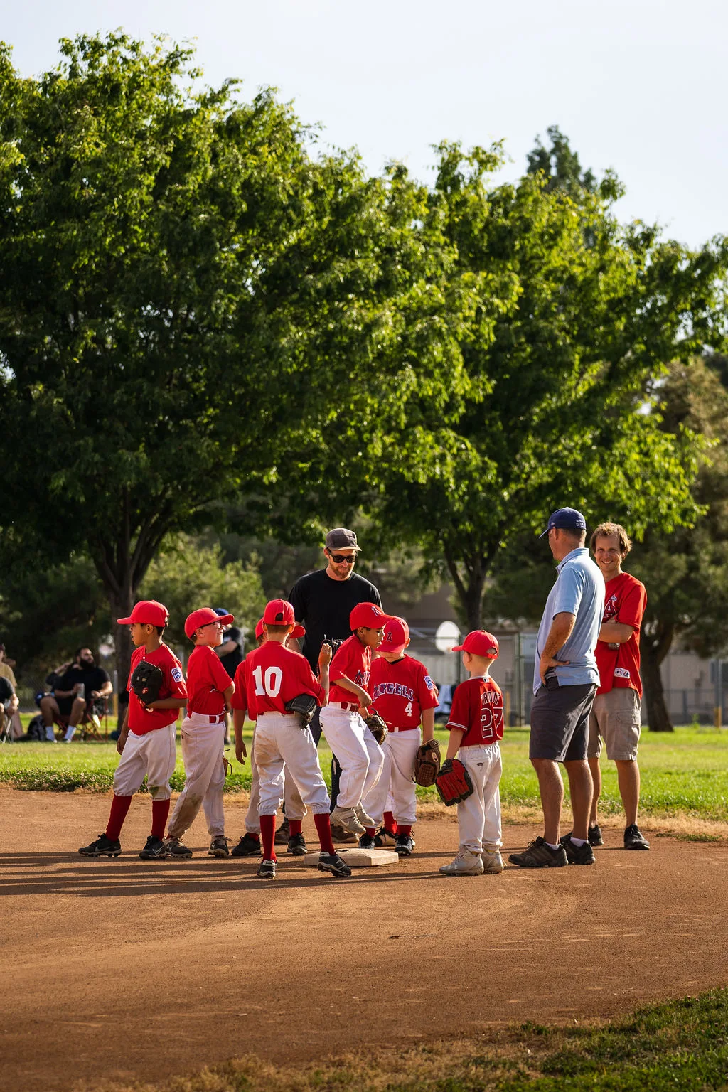 Little league Angels team huddle with coaches at the mound